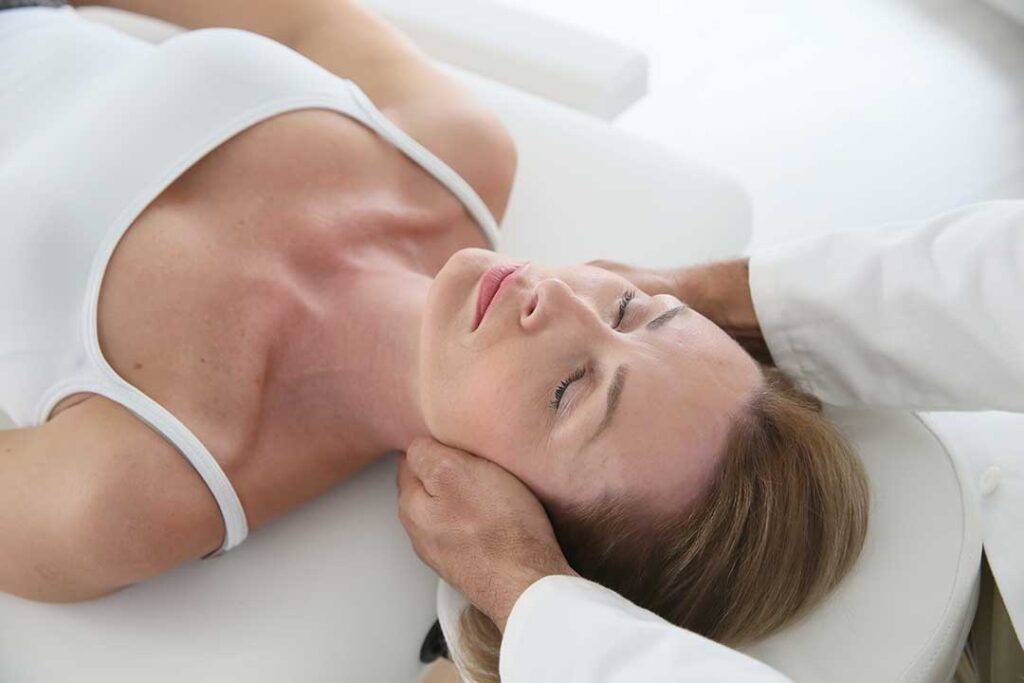 A person gently massaging their jaw while sitting in a home office with good posture.